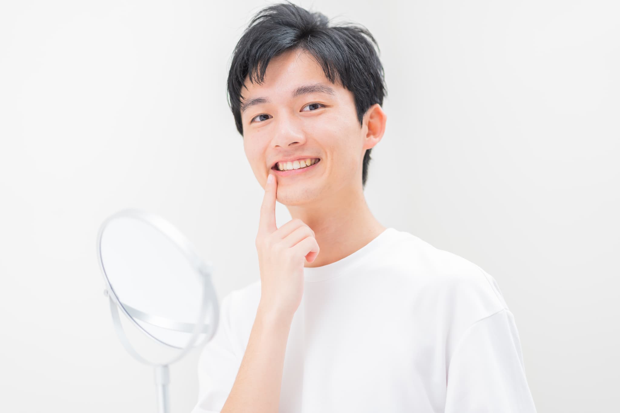 ホワイトニングで白くなった歯を指さす男性