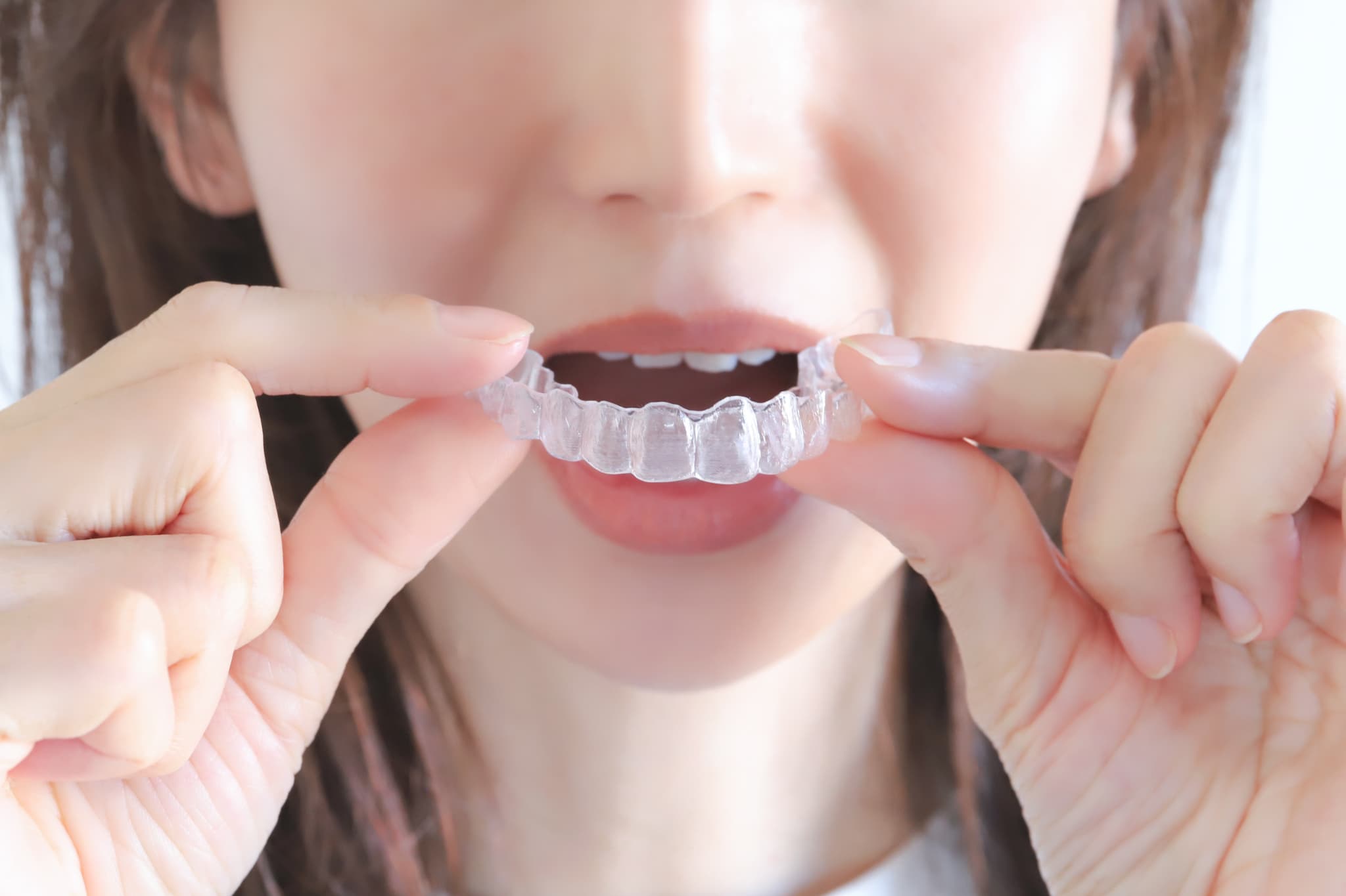 マウスピース矯正の装置を両手で持つ女性