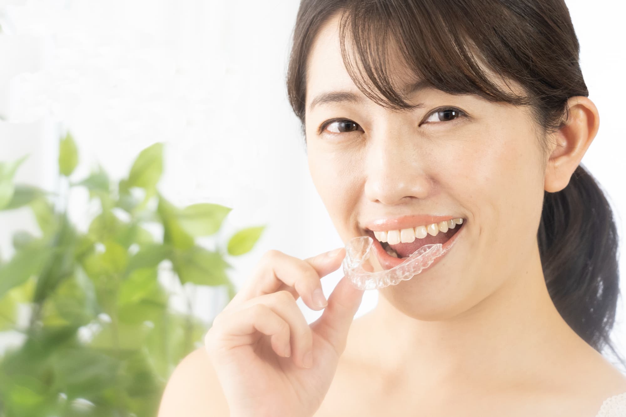 マウスピース矯正の装置を装着しようとしている笑顔の女性