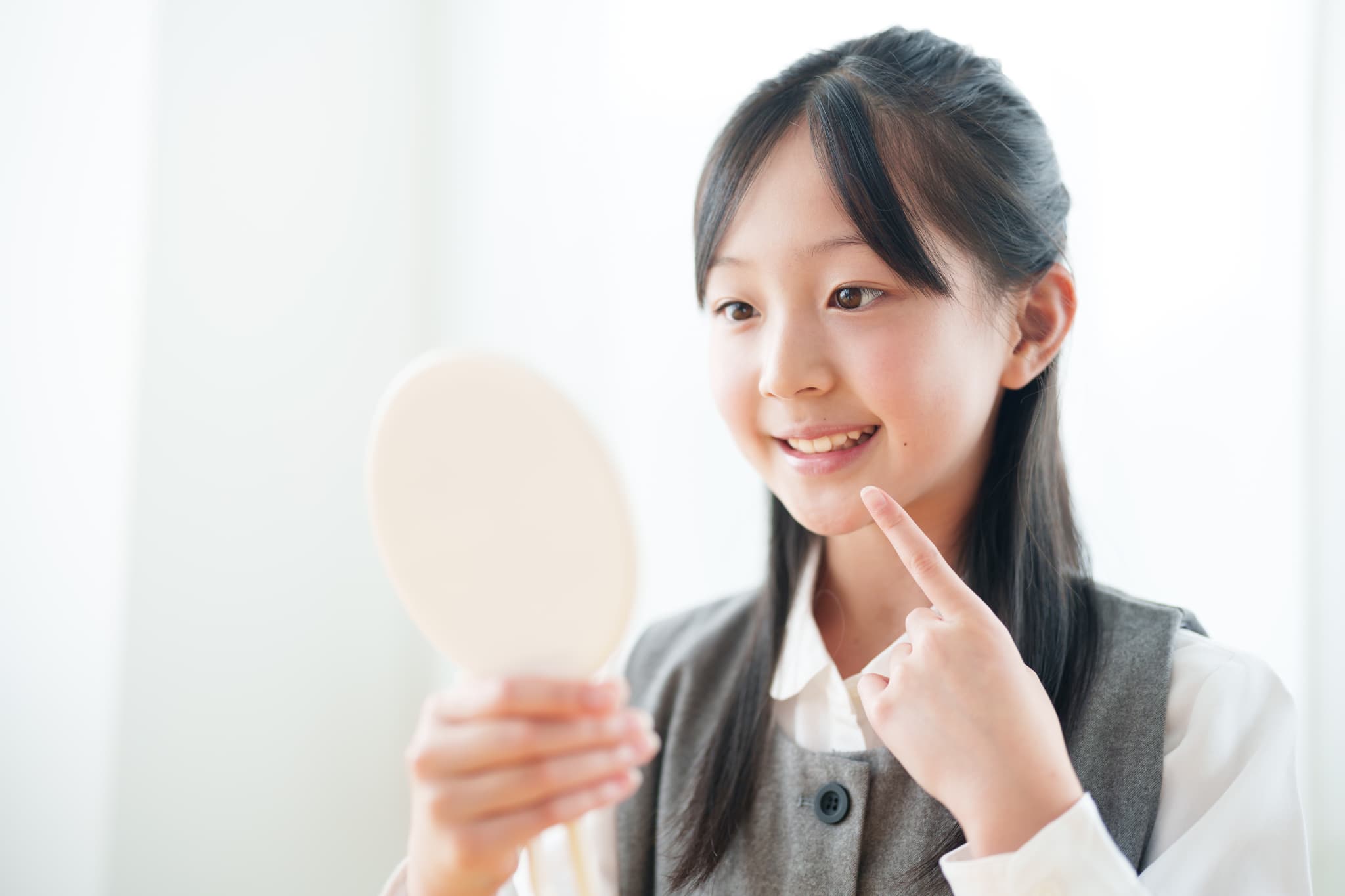 歯並びを鏡で確認する女の子