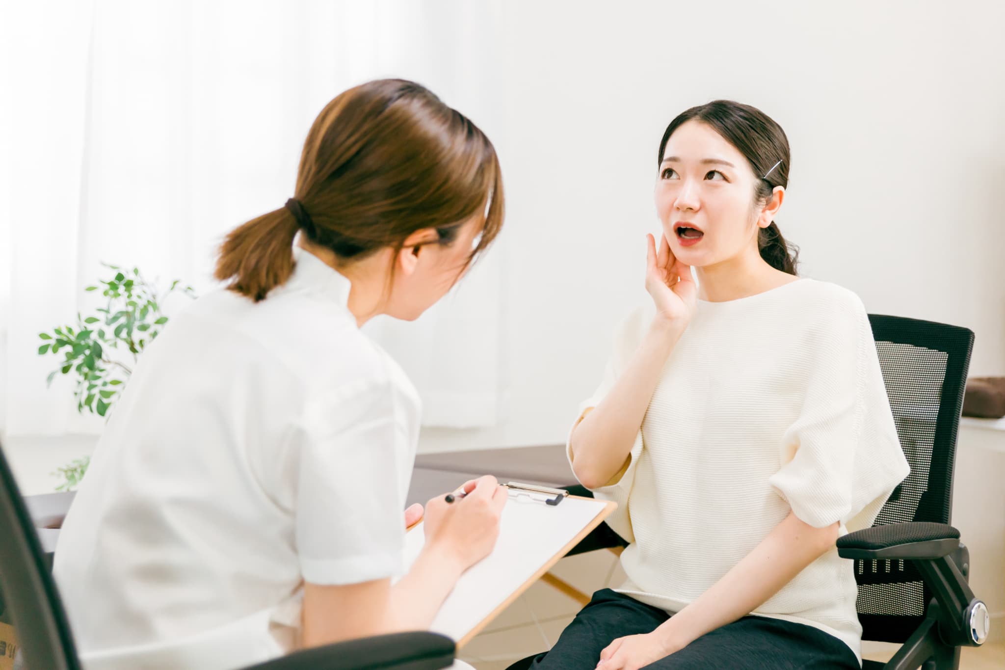 顎関節症の診断をする歯科医師と口を開けて診察を受ける女性