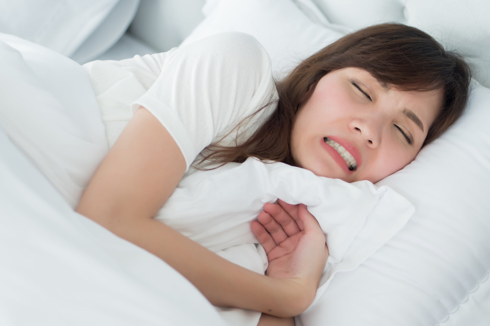 セラミックの歯の寿命が短くなる歯ぎしりをしながら眠る女性