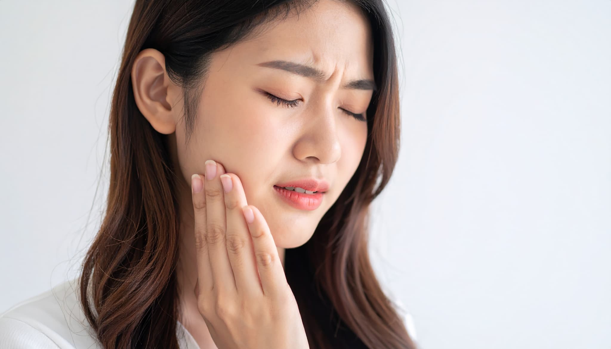 歯の痛みを感じ口元を押さえる女性